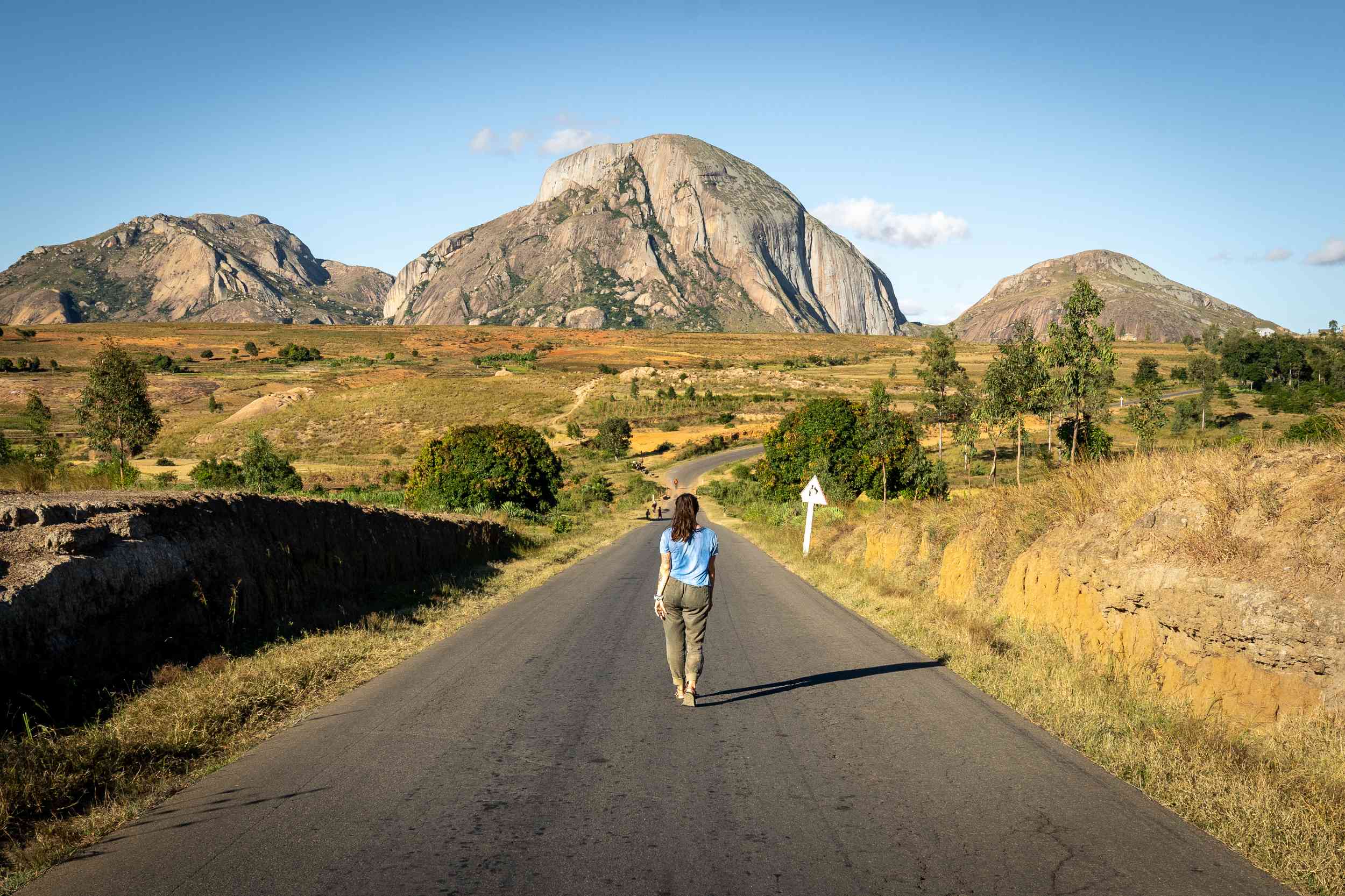 Femme qui marche sur une route face au montagnes