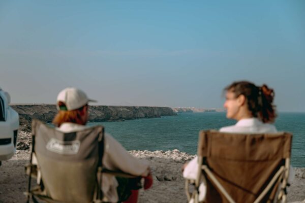 Deux personnes assises dans des chaises de camping face à la mer à Oman