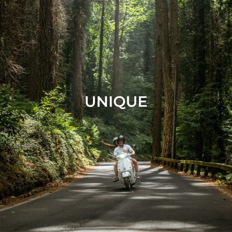 Zwei Menschen auf ihrer Vespa fahren durch einen Wald an der Amalfiküste – ein unvergesslicher Italien Vespa Roadtrip.