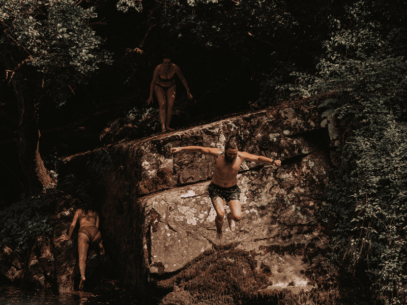 women jumping off cliff into water