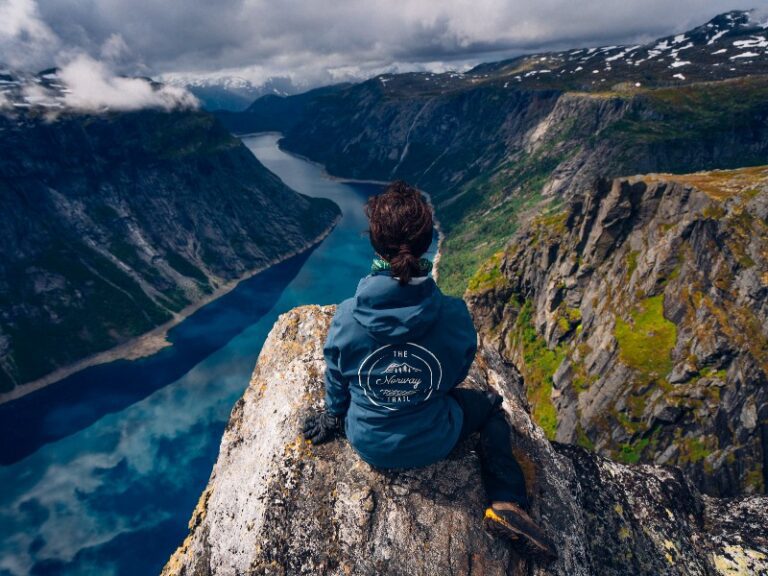 Een gids die over een rots op Trolltunga leunt