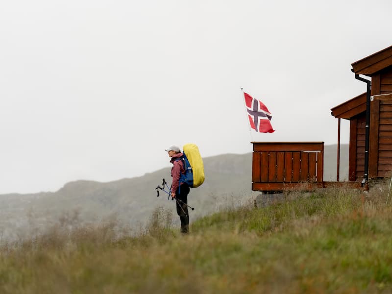 Een persoon naast een vlag van Noorwegen.