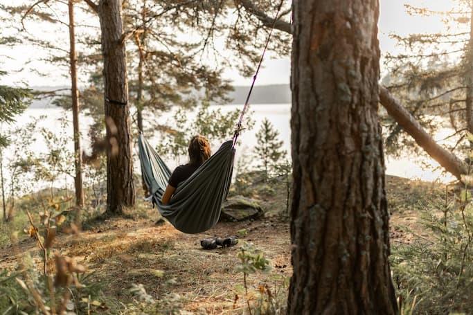 Une voyageuse dans un hamac entre deux arbres.