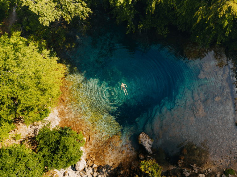 Blue eye en Albanië met een zwemmer tijdens de wandeling op de Peaks of the Balkans.