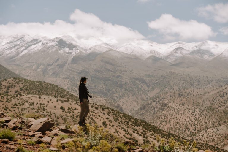 un randonneur qui profite de la vue sur les montagnes enneigées de l'Atlas au Maroc