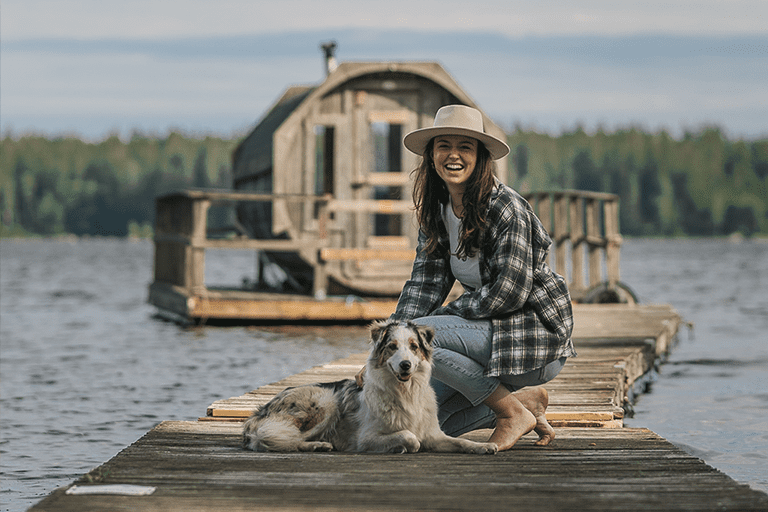 Woman with a dog in front of the sauna by the lake.