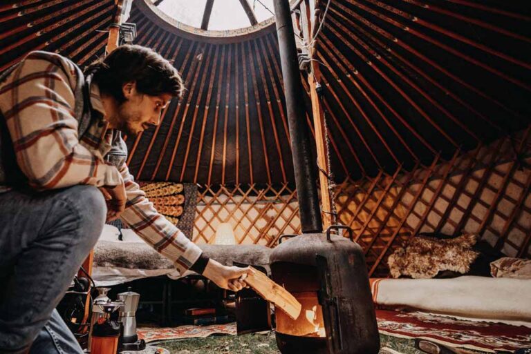 Man die de haard stookt in een yurt in Drenthe